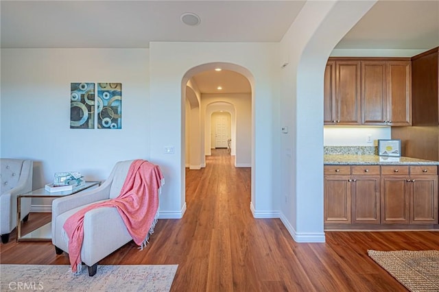 hall with dark wood-type flooring, arched walkways, baseboards, and recessed lighting