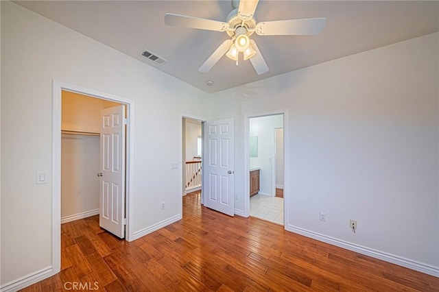 unfurnished bedroom featuring baseboards, visible vents, wood finished floors, a spacious closet, and a closet