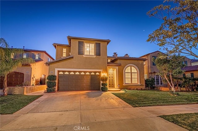 mediterranean / spanish home with a garage, driveway, a front lawn, and stucco siding