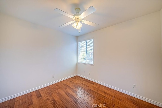 spare room with a ceiling fan, baseboards, and wood finished floors