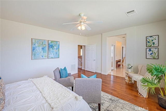 bedroom with baseboards, ceiling fan, visible vents, and wood finished floors