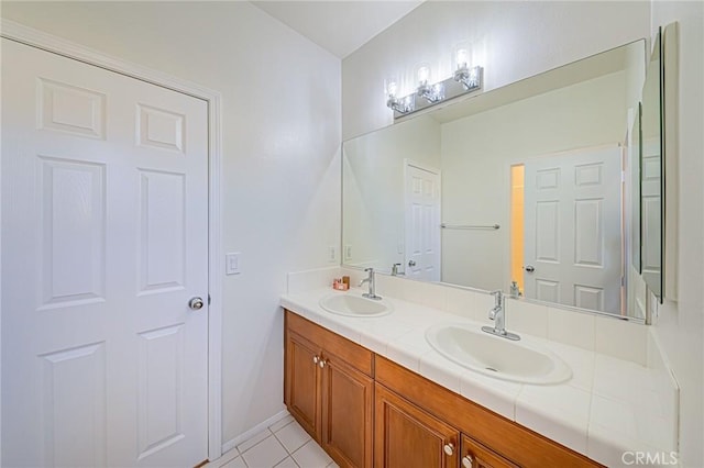 full bathroom with double vanity, tile patterned flooring, baseboards, and a sink