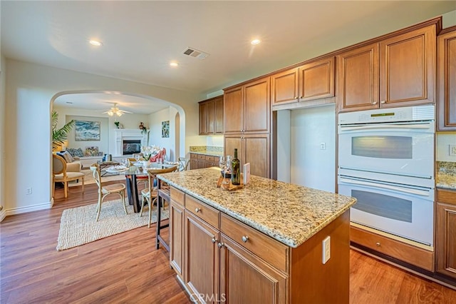 kitchen featuring brown cabinets, visible vents, a kitchen island, and white double oven