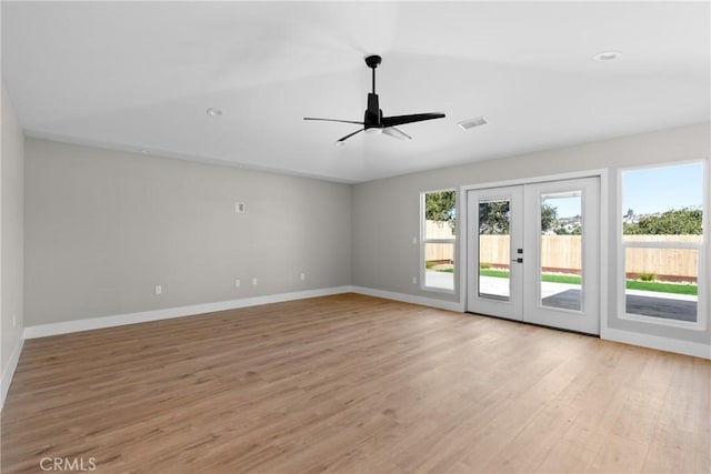 spare room featuring light wood-style floors, visible vents, and vaulted ceiling