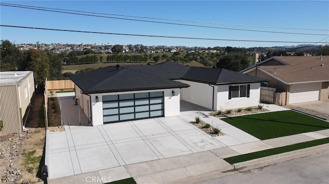 view of front of property featuring concrete driveway, fence, an attached garage, and stucco siding