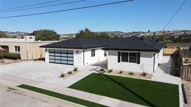 view of front facade featuring stucco siding, an attached garage, fence, driveway, and a front lawn