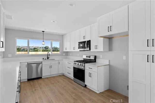 kitchen featuring white cabinets, appliances with stainless steel finishes, light countertops, and a sink