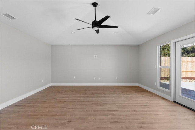 empty room featuring light wood-type flooring, baseboards, visible vents, and vaulted ceiling