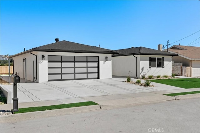 view of front of house featuring a garage, concrete driveway, fence, and stucco siding