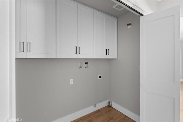 clothes washing area with cabinet space, baseboards, visible vents, gas dryer hookup, and wood finished floors