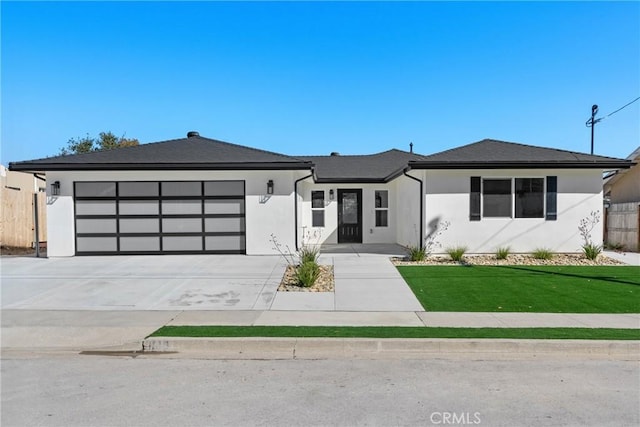 view of front of property featuring concrete driveway, a front yard, an attached garage, and stucco siding