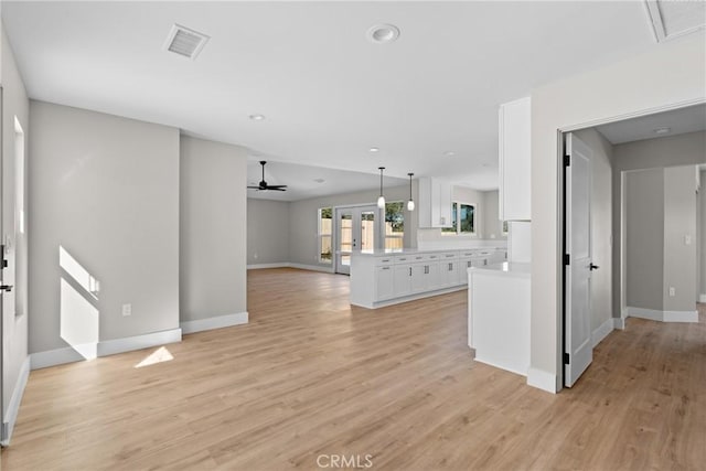 unfurnished living room with ceiling fan, light wood-type flooring, visible vents, and baseboards