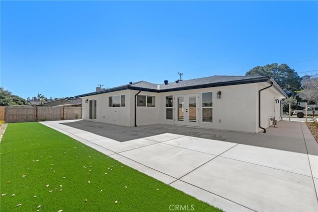 rear view of house featuring a patio, a lawn, fence, and stucco siding