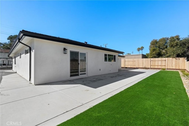 back of property with a patio area, a yard, fence, and stucco siding