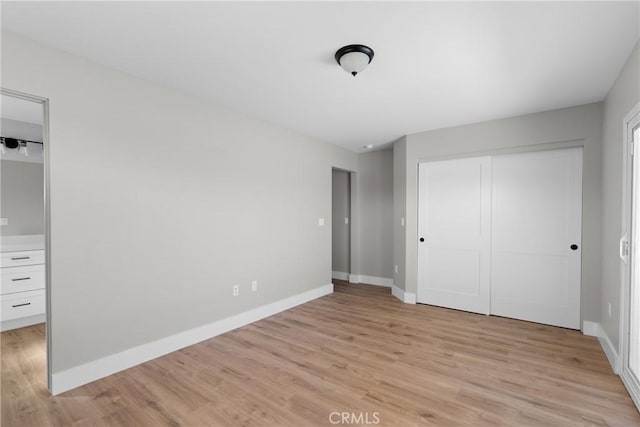 unfurnished bedroom featuring light wood finished floors, a closet, and baseboards