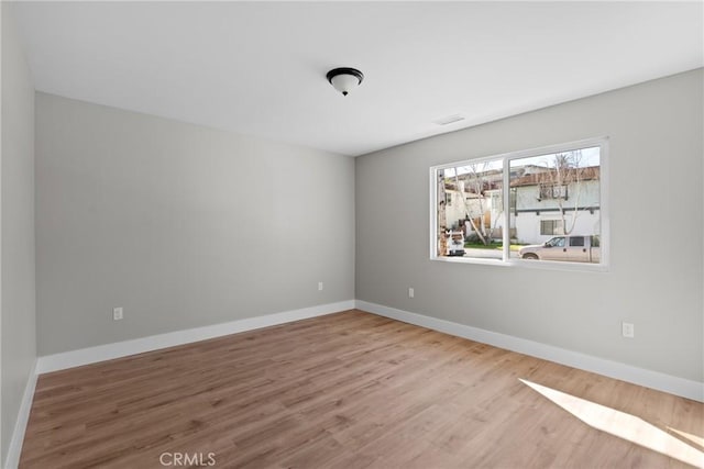 empty room with light wood-style flooring and baseboards