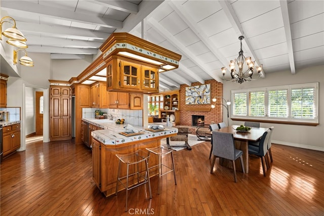 kitchen featuring brown cabinetry, a brick fireplace, light countertops, and a kitchen breakfast bar