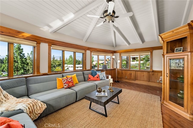 living area featuring vaulted ceiling with beams, ceiling fan, a wainscoted wall, wood walls, and wood finished floors