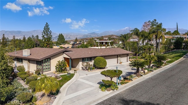 ranch-style house featuring a garage, concrete driveway, and a mountain view