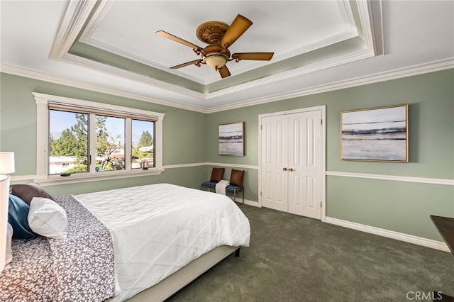 bedroom with baseboards, a tray ceiling, dark colored carpet, and a closet