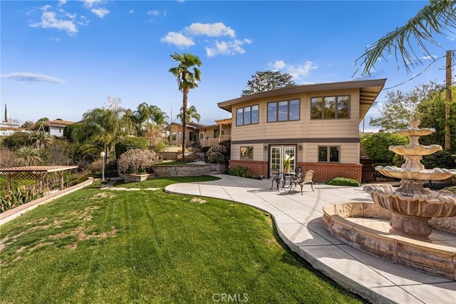 rear view of property featuring a yard, a patio area, and brick siding