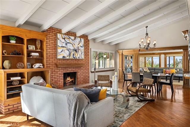 living area with a chandelier, a brick fireplace, vaulted ceiling with beams, and hardwood / wood-style flooring