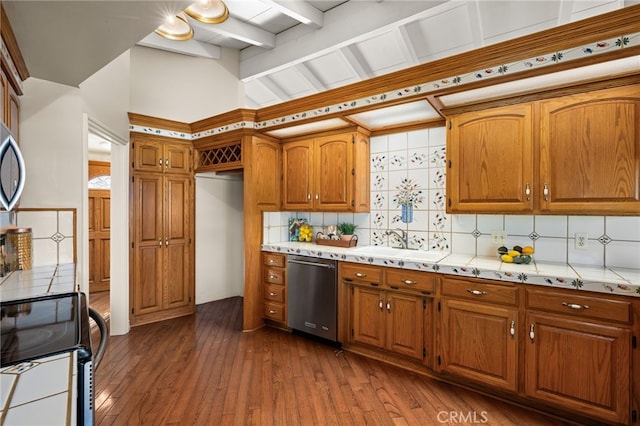 kitchen featuring light countertops, appliances with stainless steel finishes, a sink, and brown cabinets