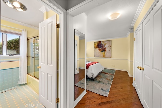 hall featuring baseboards, wood finished floors, and crown molding