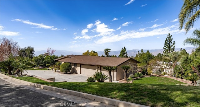 exterior space with driveway, an attached garage, a mountain view, and a front yard