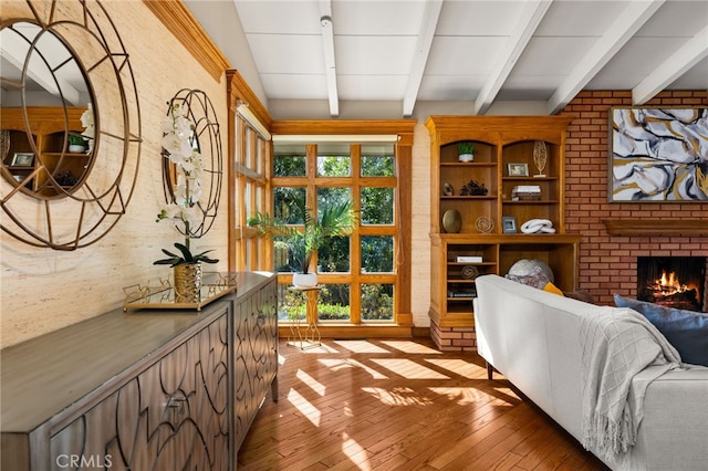 living area with light wood-style floors, plenty of natural light, a fireplace, and beamed ceiling