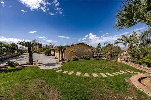 view of yard with driveway and a patio