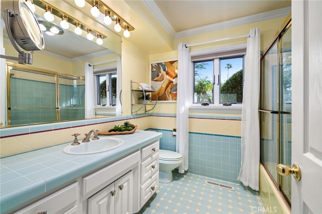 full bathroom featuring crown molding, tile walls, visible vents, wainscoting, and combined bath / shower with glass door