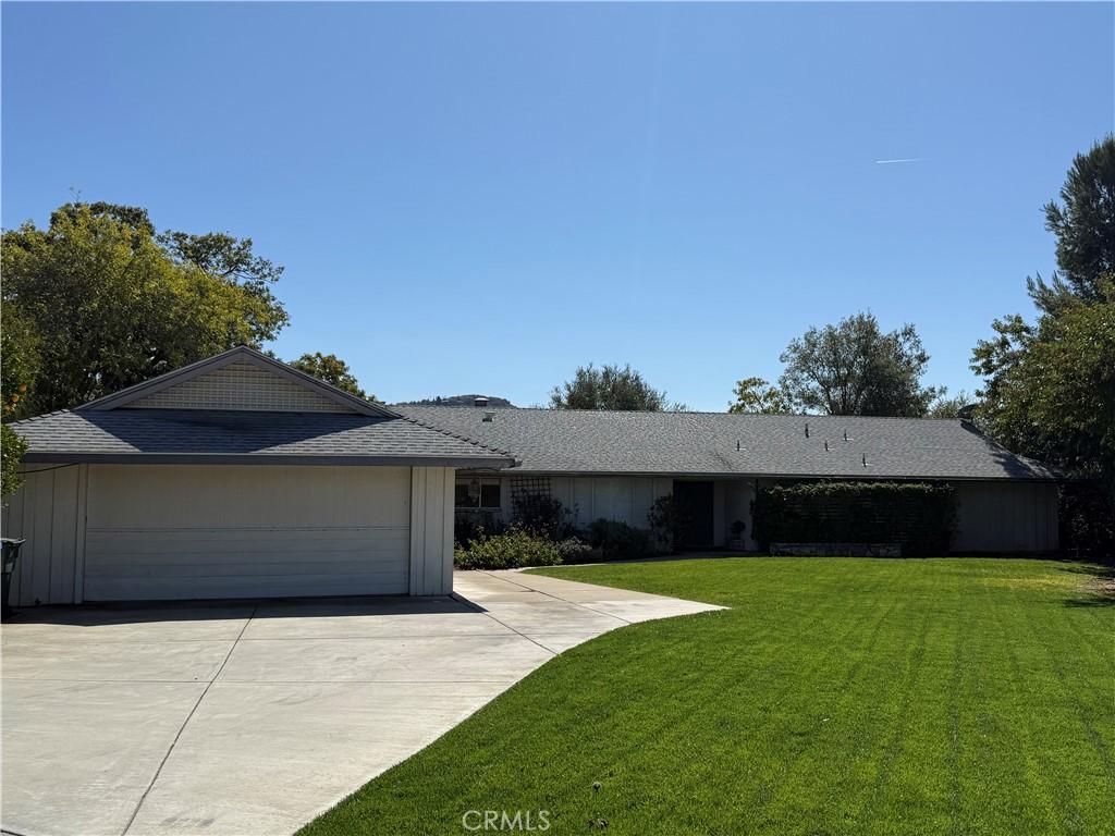 ranch-style house featuring a garage, concrete driveway, board and batten siding, and a front yard