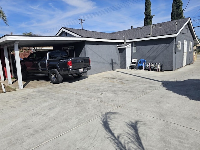 view of property exterior with driveway, a shingled roof, a carport, and stucco siding