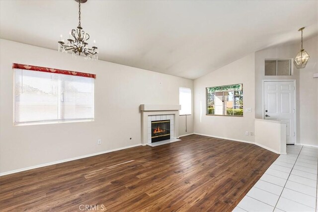 40292 Corte Delfin, Murrieta, CA 92562 - unfurnished living room with wood finished floors, baseboards, a fireplace, vaulted ceiling, and a chandelier