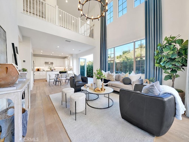 living area with recessed lighting, an inviting chandelier, and light wood-style floors