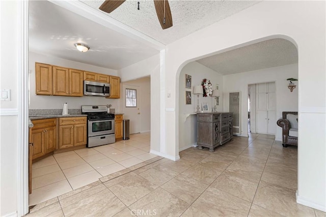 kitchen with arched walkways, light tile patterned floors, a textured ceiling, and stainless steel appliances