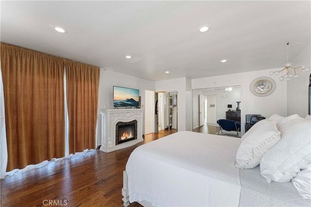 bedroom with a glass covered fireplace, recessed lighting, and wood finished floors