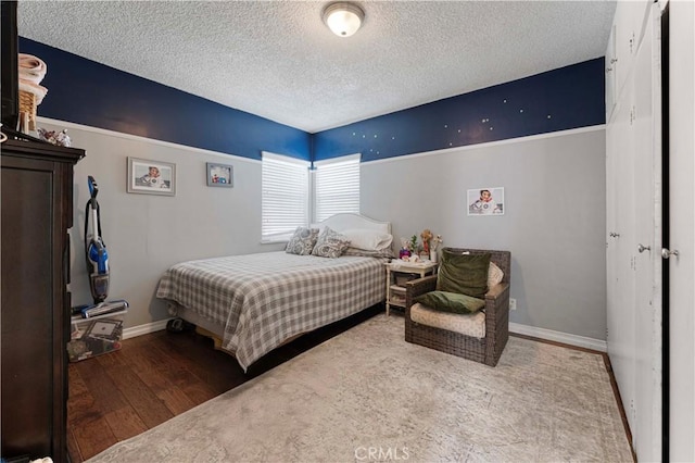 bedroom with wood finished floors, baseboards, and a textured ceiling