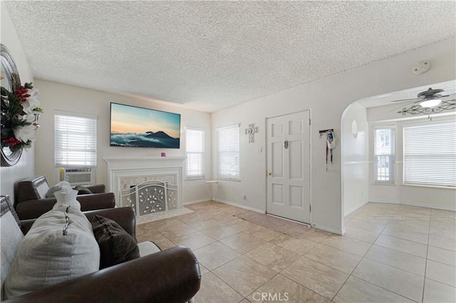 living area featuring a fireplace with flush hearth, a healthy amount of sunlight, arched walkways, and light tile patterned floors