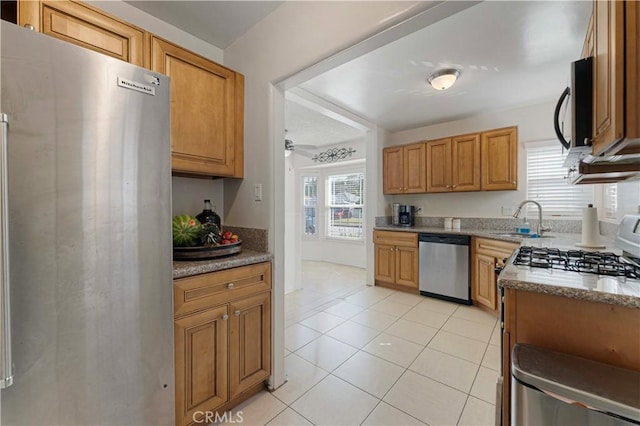 kitchen featuring a sink, brown cabinets, appliances with stainless steel finishes, and light tile patterned floors