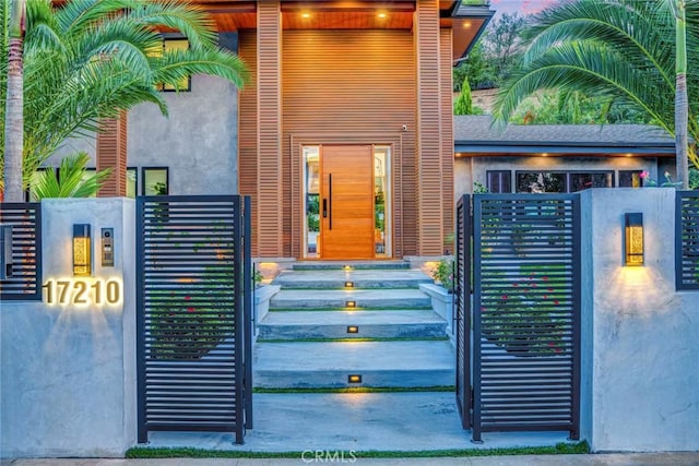 exterior space with a gate, fence, and stucco siding