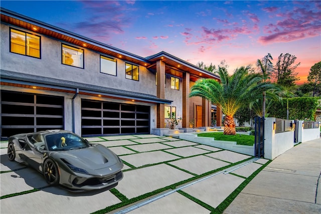 view of front facade with a garage, concrete driveway, fence, and stucco siding