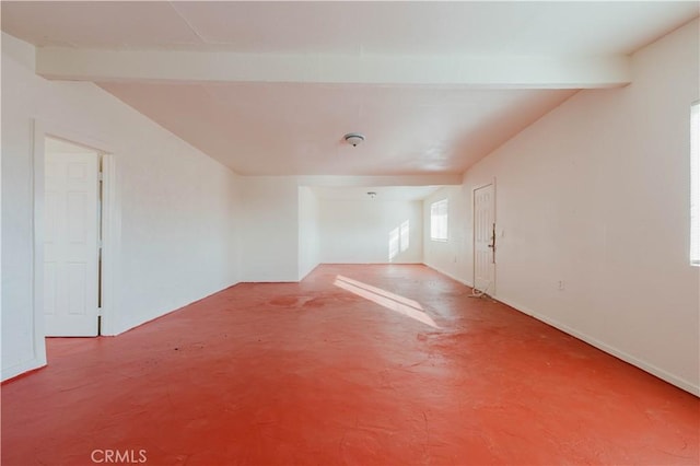 empty room with vaulted ceiling with beams and concrete floors