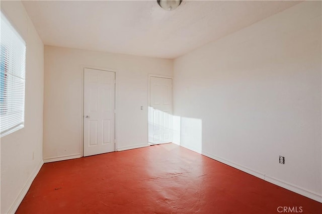 spare room featuring concrete flooring and baseboards