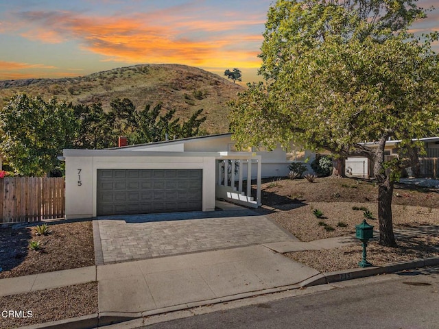 view of front of house featuring a garage, stucco siding, a mountain view, and fence