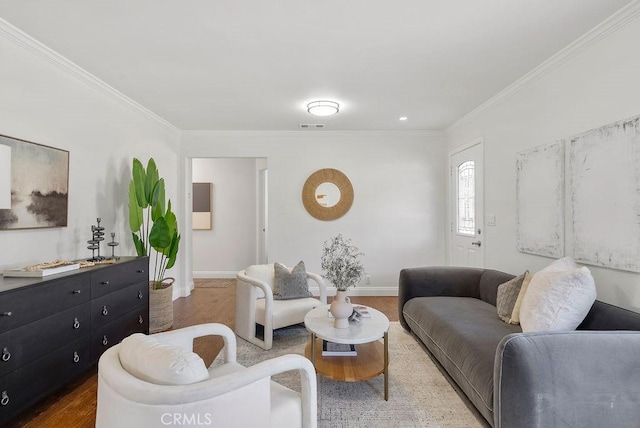 living room with baseboards, wood finished floors, visible vents, and crown molding