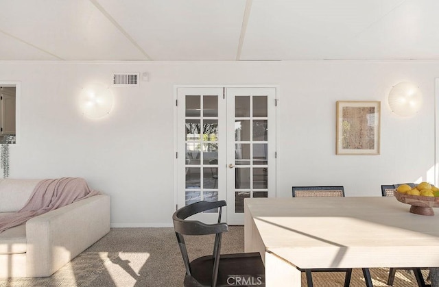 carpeted dining space featuring baseboards, visible vents, and french doors