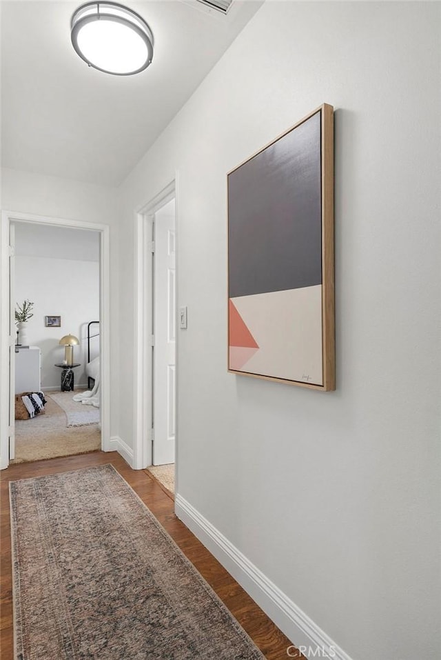 hallway featuring wood finished floors and baseboards