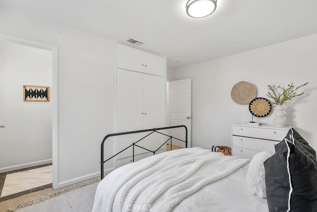 bedroom with baseboards, visible vents, and a closet